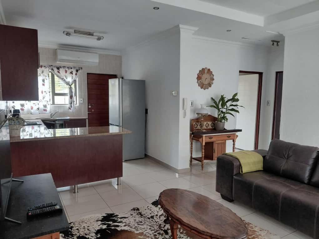 ein Wohnzimmer mit Couch und Küche in der Unterkunft Agapantha Cottage in Ezulwini