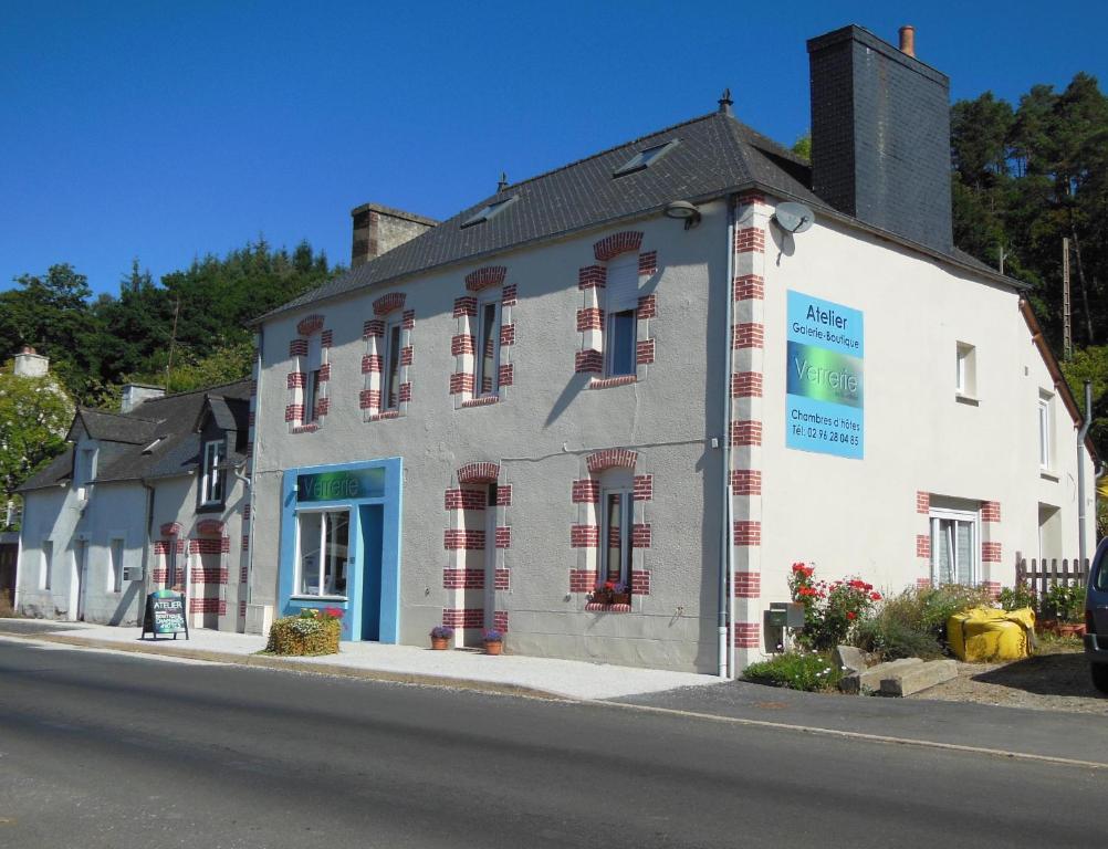 un bâtiment blanc sur le côté d'une rue dans l'établissement La Verrerie de Guerlédan, à Caurel