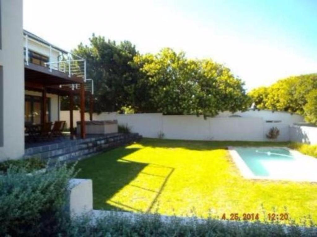 a large yard with a pool and a house at Riverside 18 in Hermanus