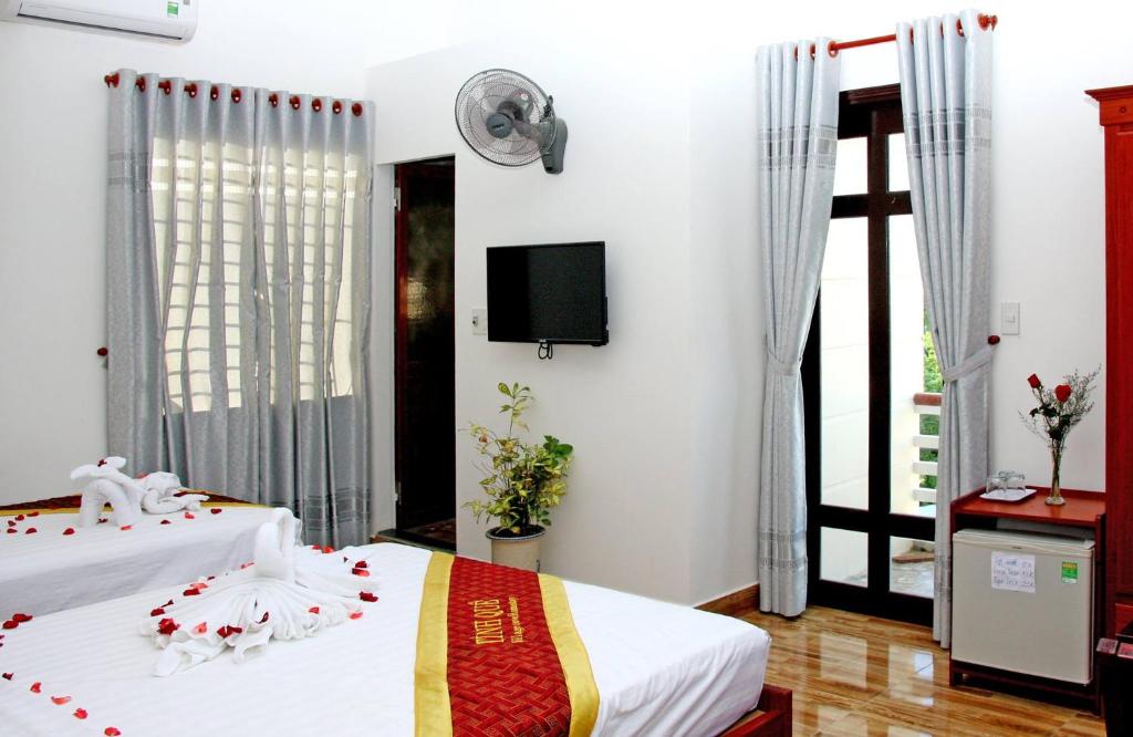 1 dormitorio con 1 cama y TV en la pared en Village Love Homestay, en Hoi An