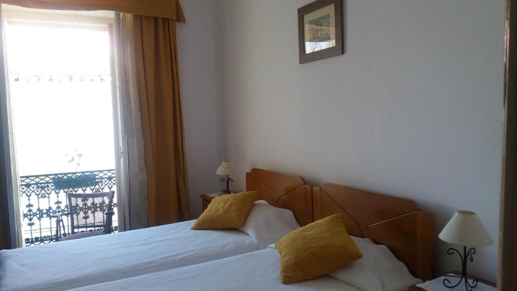 ein Schlafzimmer mit einem Bett mit gelben Kissen und einem Fenster in der Unterkunft Solar Dos Viscondes - Turismo De Habitacao in Ferreira do Alentejo