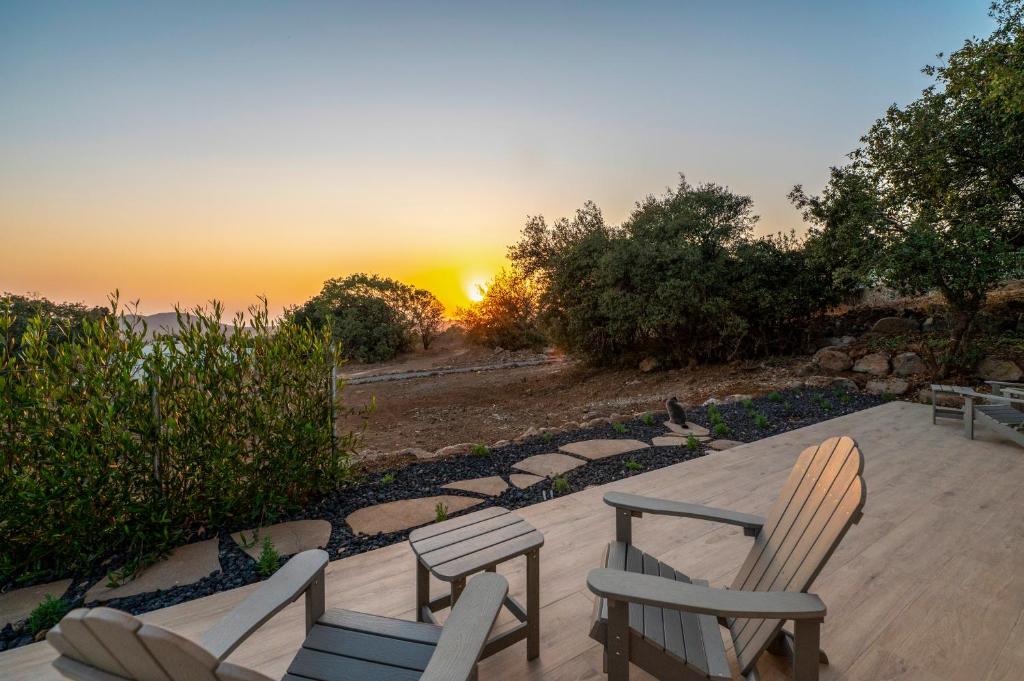 a patio with two chairs and a sunset in the background at Shifon Ein Zivan in Ein Zivan