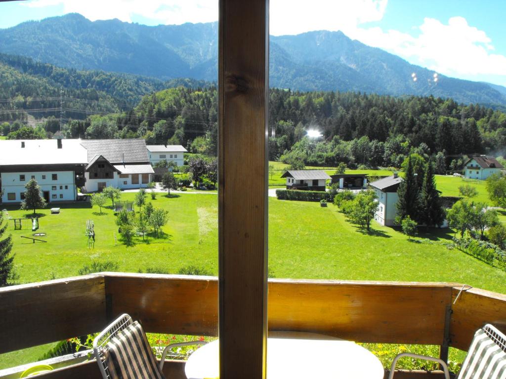 einen Balkon mit Blick auf ein grünes Feld und die Berge in der Unterkunft Olympia Apartment in Latschach ober dem Faakersee
