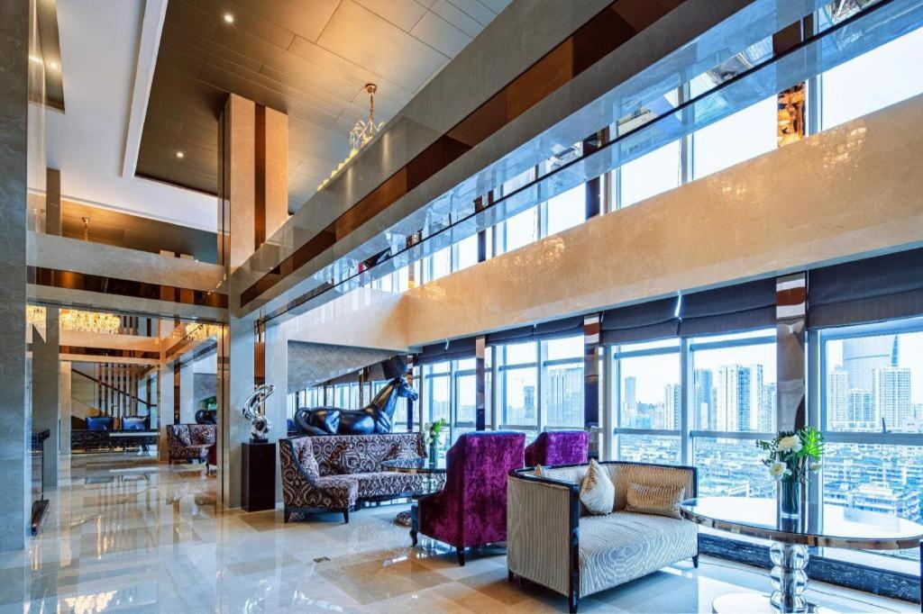 eine Lobby mit Stühlen und einem Tisch und Fenstern in der Unterkunft Chengdu Rising Butterfly Hotel in Chengdu