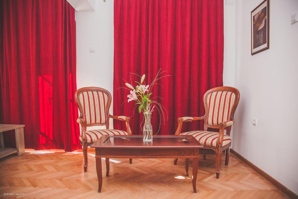 a room with two chairs and a table with a vase of flowers at Apartments Konak in Visoko