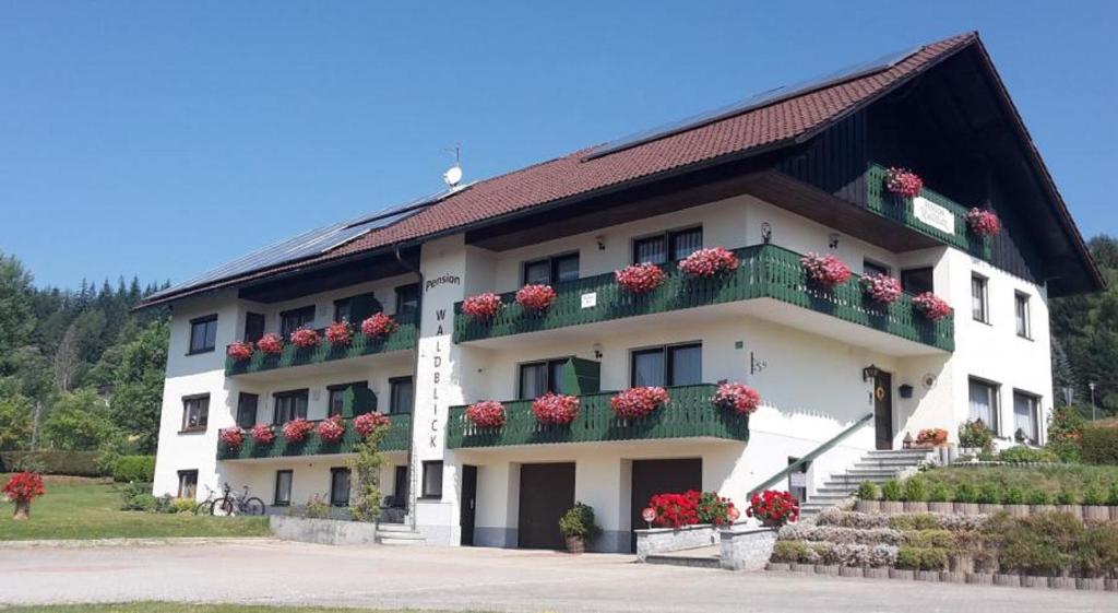 a large white building with flowers on the balconies at Pension Waldblick in Bayerisch Eisenstein