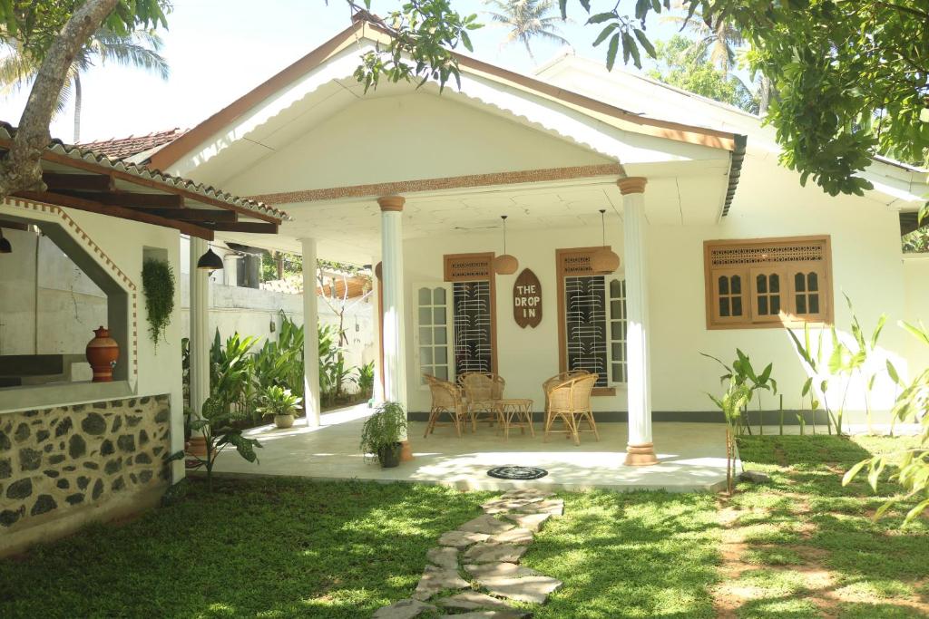 a white house with a porch and a patio at The Drop In Surfhouse Madiha in Madihe East