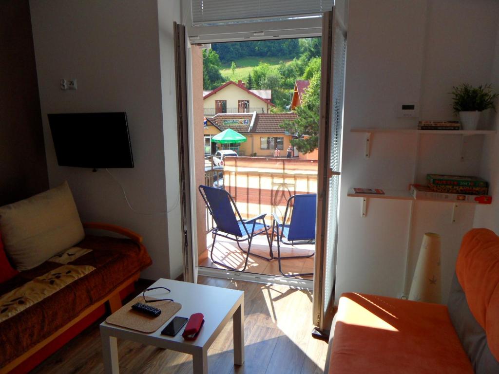 a living room with a couch and a view of a balcony at Apartament Kraszewskiego in Krynica Zdrój