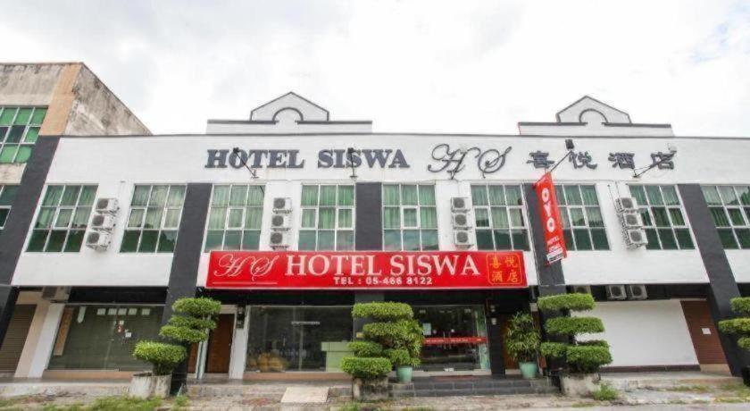 a hotel with a red sign in front of a building at OYO 89539 Hotel Siswa in Kampar