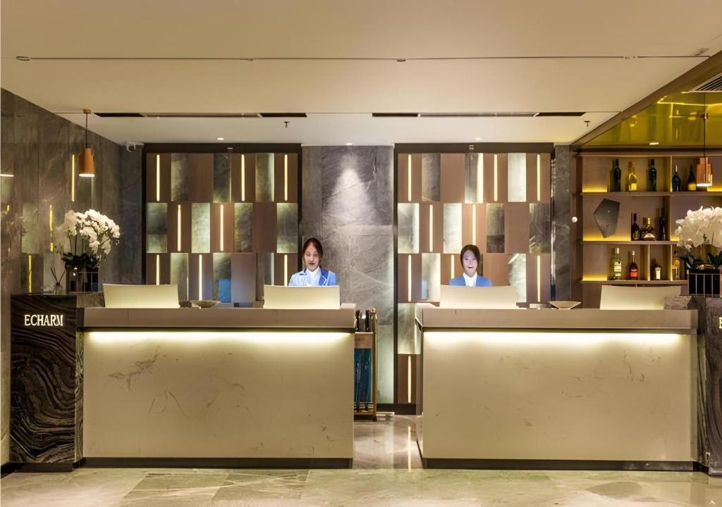 zwei Frauen sitzen an einer Theke in einer Hotellobby in der Unterkunft Echarm Hotel Shenyang Nanta Shoe City Army General Hospital in Shenyang