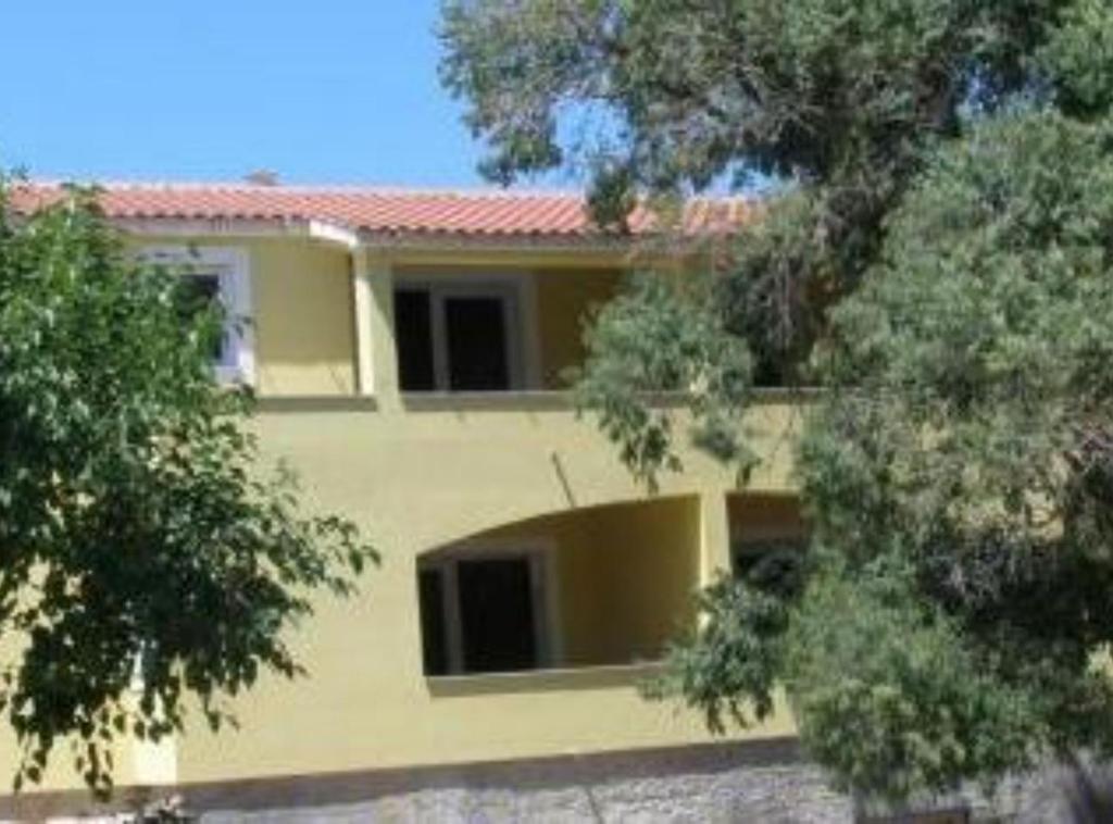 a yellow house with a red roof and some trees at Apartments Snježana in Sali