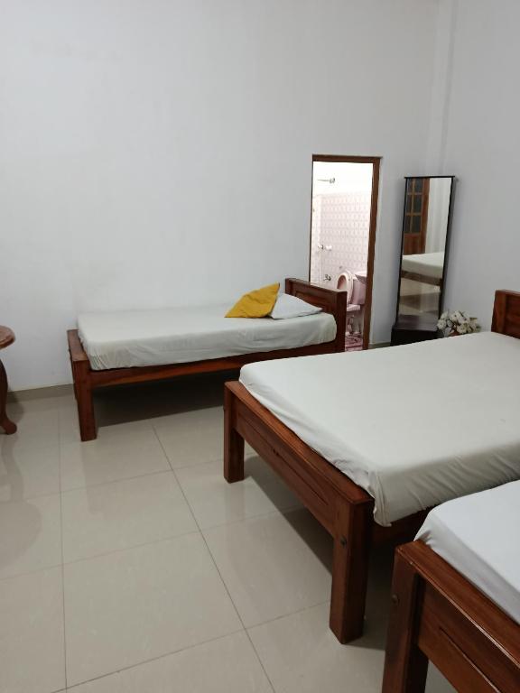 une chambre avec trois lits et un miroir dans l'établissement Wild Safari, à Tissamaharama