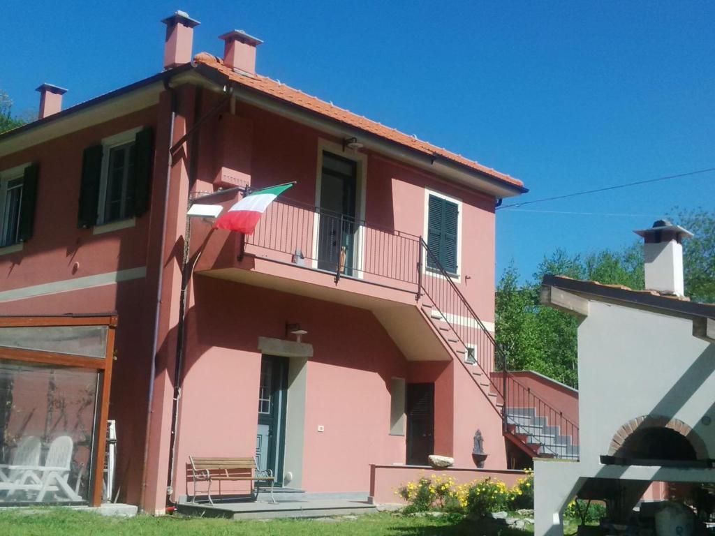 una casa rosa con una bandera en el balcón en Da Laura e Sergio, en Vezzi Portio