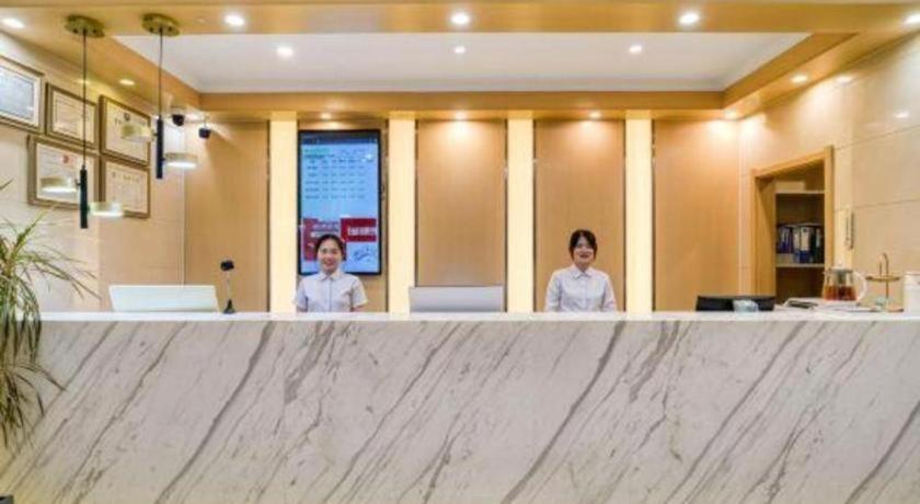 zwei Frauen stehen hinter einer großen Marmortheke in der Unterkunft GreenTree Inn Jiaxing ZhongHuan South Road Zhonggang City Express Hotel in Jiaxing