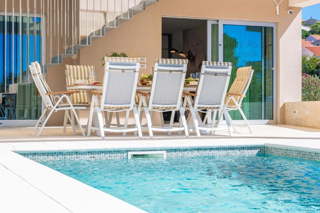 a patio with a table and chairs next to a swimming pool at Villa Axia Šibenik in Šibenik