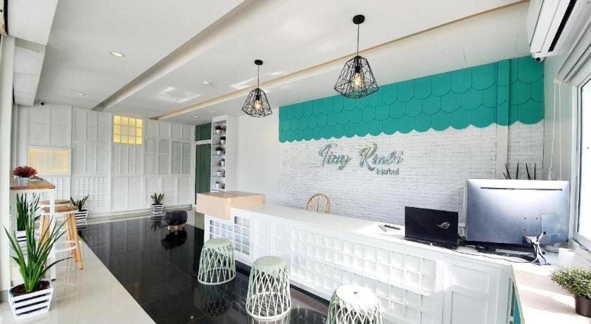 a restaurant with a counter with chairs and a television at Tiny Krabi Hotel in Ban Ta Kun