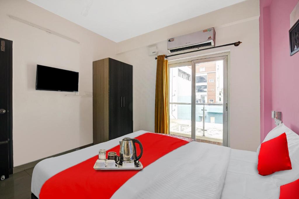 a bedroom with a red and white bed and a window at Hotel O VSV Avenue Hennur in Bengaluru