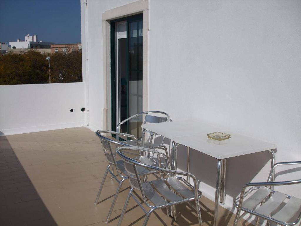 einen weißen Tisch und Stühle auf einem Balkon mit Fenster in der Unterkunft Hotel Adelaide in Faro