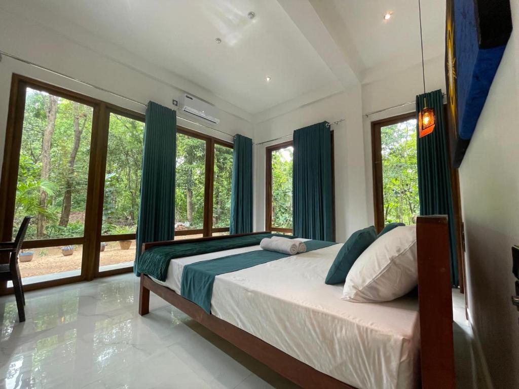 a bedroom with a bed with blue curtains and windows at Sigiriya Hotel and Resort in Sigiriya