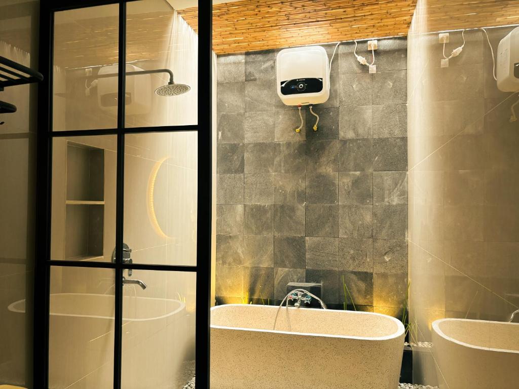 ein Badezimmer mit einer Dusche, einem Waschbecken und einer Badewanne in der Unterkunft LaVella Villa Jogjakarta kolam renang pribadi in Godean