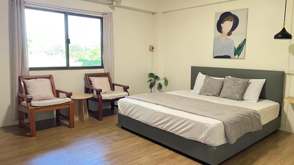 a bedroom with a large bed and two chairs at A Day Rayong in Ban Pa Khan