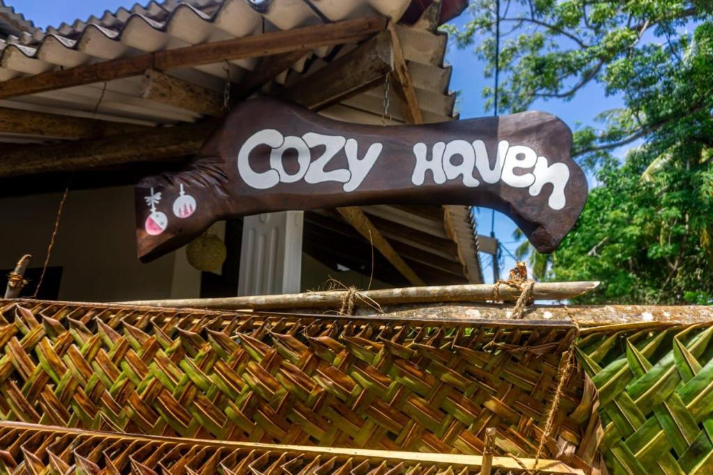 a sign that says cozyhaven on the side of a building at cozy haven in Midigama
