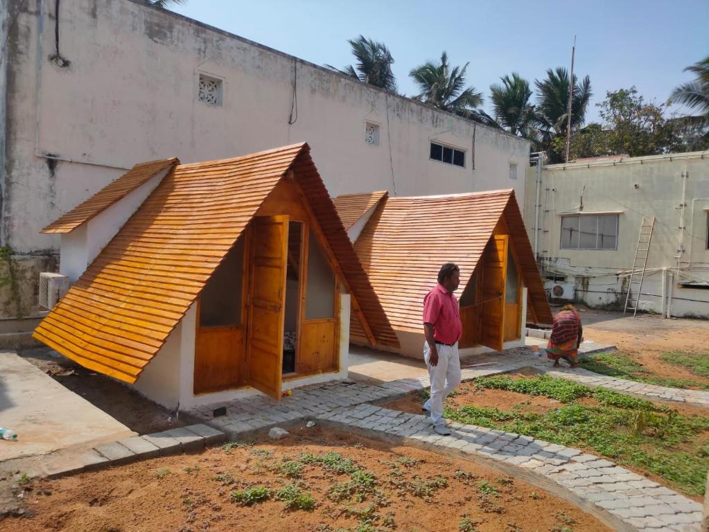 Un hombre de pie frente a una casa en construcción. en Starlit camp, en Mahabalipuram