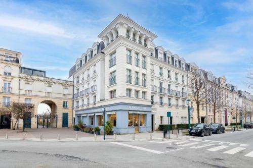 een wit gebouw op een straat met auto's aan de voorkant bij Chill' Appart Disneyland in Chessy