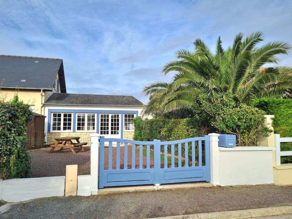 Ein blauer Zaun vor einem Haus mit einem Picknicktisch in der Unterkunft Cottage Le pêcheur du Grand Large proximité plage in Asnelles