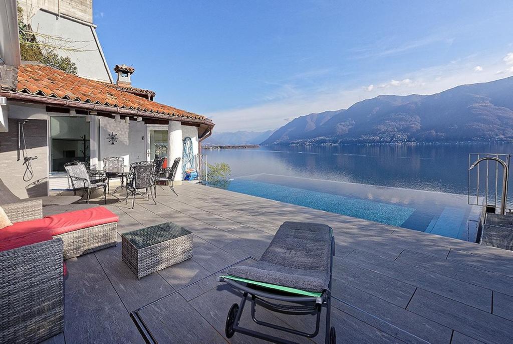 a house with a patio with a view of a lake at Casa Rondine by Fewotessin in Ronco s/Ascona - Porto Ronco