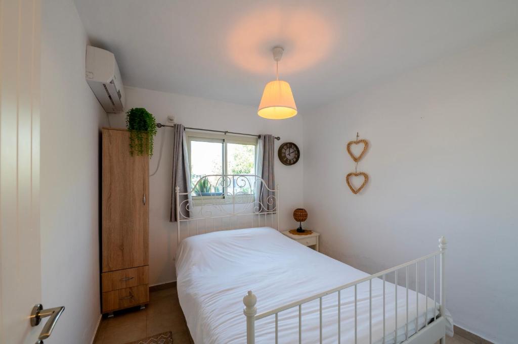a bedroom with a white bed and a window at רז אירוח ברמה- in Qasrîne
