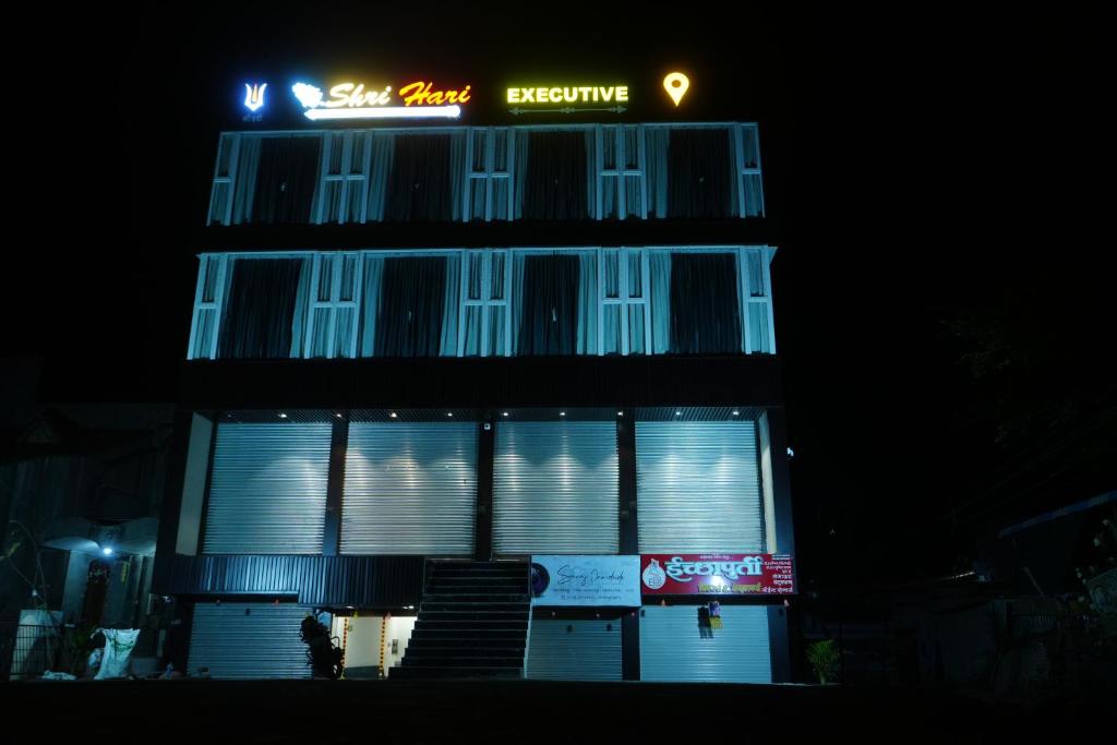 a building with a sign on top of it at night at Shri Hari Executive Lodge in Tuljapur
