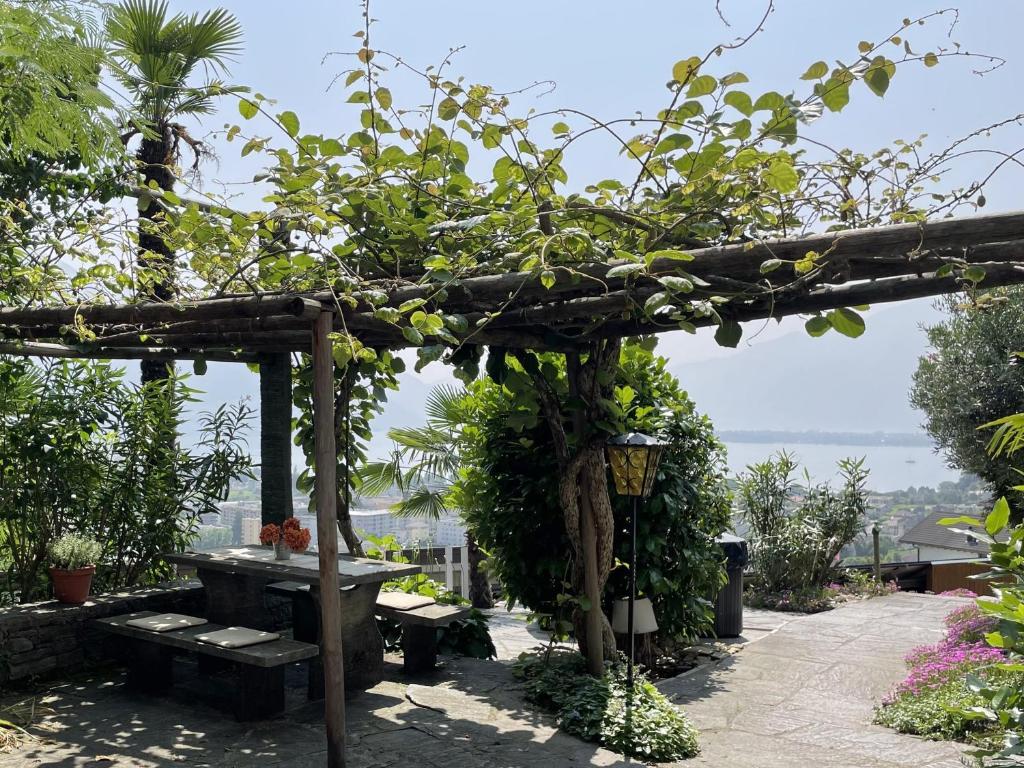 a wooden pergola with a bench and a table at Casa Colombina Duplex by Fewotessin in Gordola
