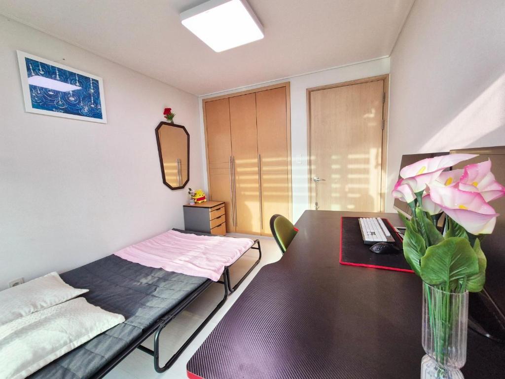 a room with a bed and a table with a vase of flowers at Healing Gangchu in Anyang