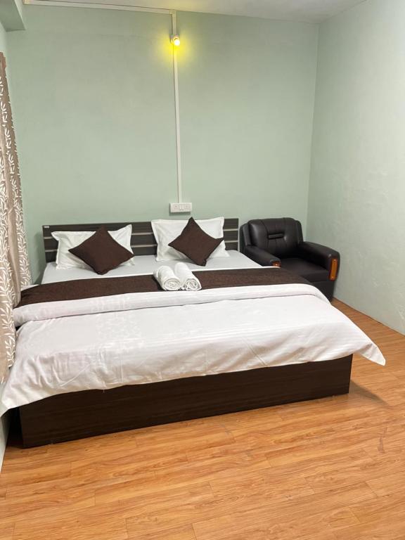 ein Schlafzimmer mit einem großen Bett und einem Stuhl in der Unterkunft Hotel Tashi Tseleng in Tawang