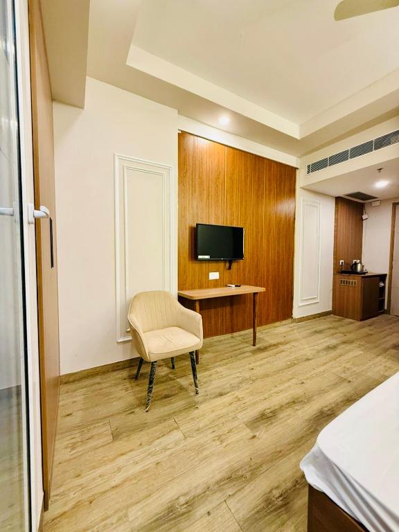 a room with a chair and a desk and a television at SR Luxury steys in Greater Noida