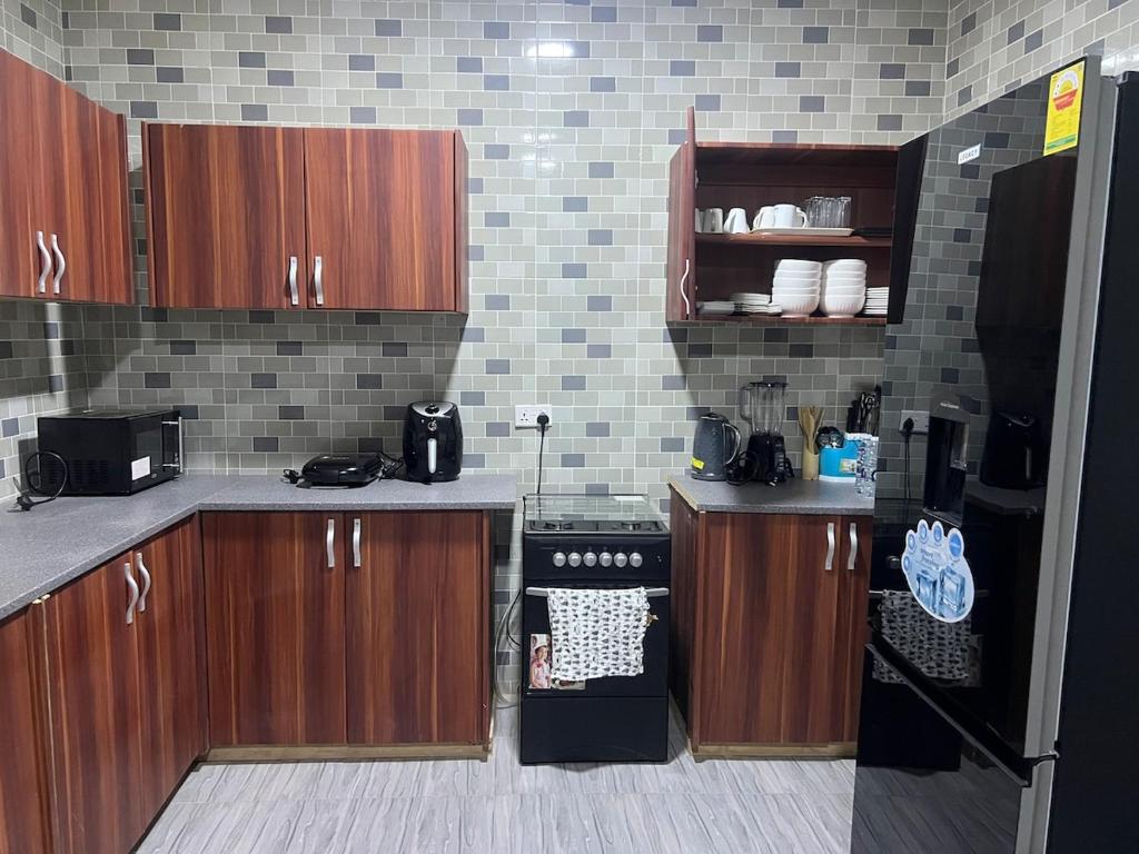 een keuken met houten kasten en een zwarte koelkast bij Entire home in Haatso in Ashonman