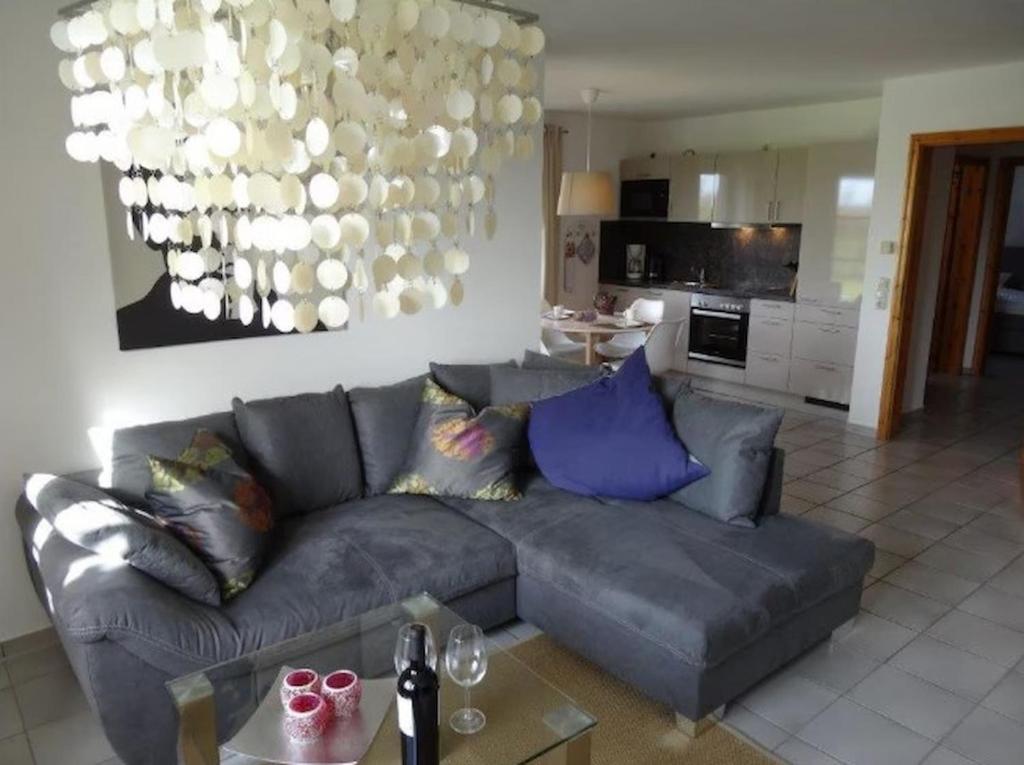a living room with a gray couch and a chandelier at Design Wohnung in Petersdorf auf Fehmarn