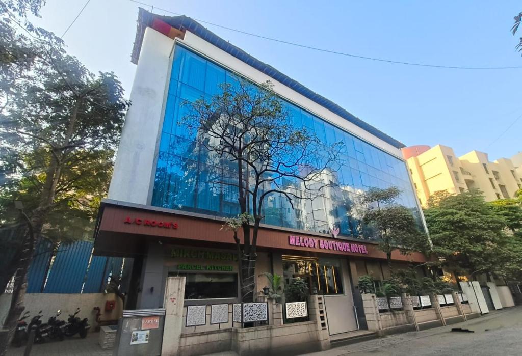 een gebouw met een weerspiegeling van een boom erop bij Hotel Melody Boutique Thane in Thane