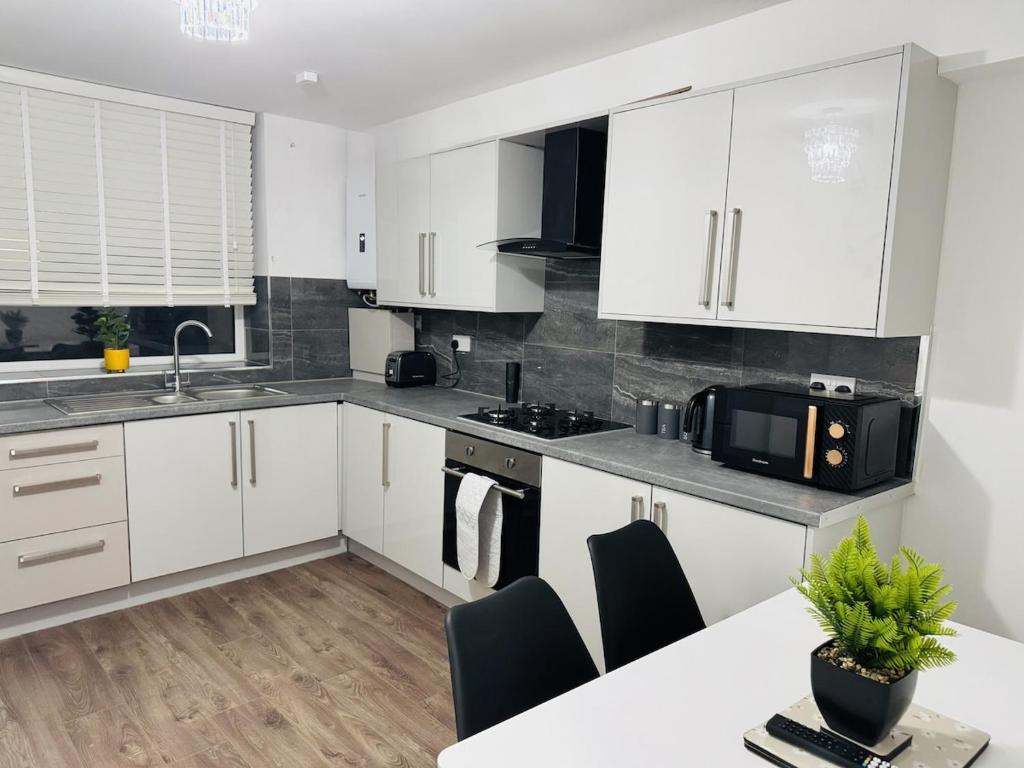 a kitchen with white cabinets and a table with chairs at Modern 1BR Home in Clayton-le-moors in Clayton le Moors