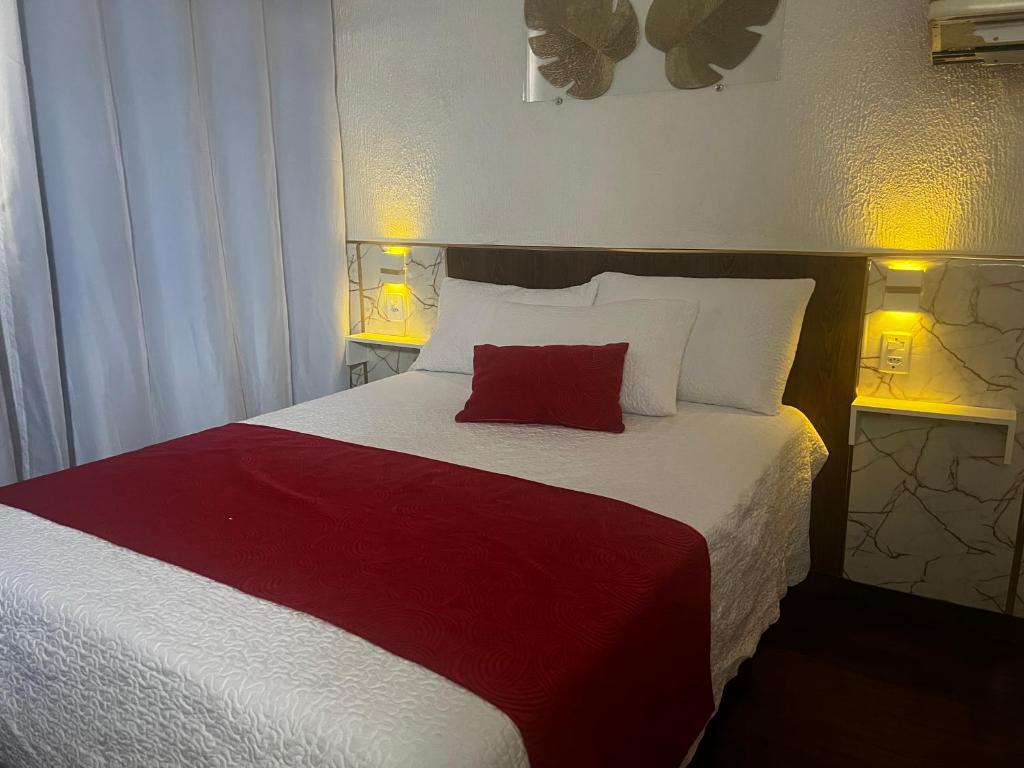 een bed met daarop een rood kussen bij Recanto Guaraú 2 in Peruíbe