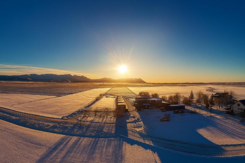 Una vista aérea de un campo nevado con la puesta de sol. en The Hvítá Inn by Ourhotels, en Bær