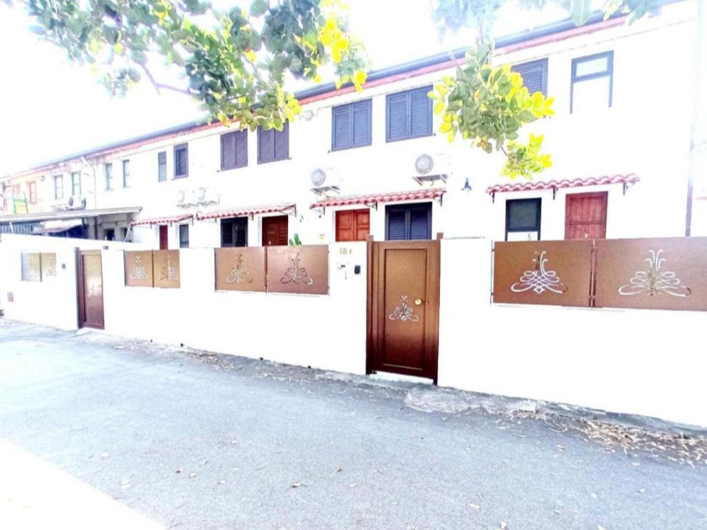 a white building with brown doors and a fence at Fontanarossa Airport Sleep and Travel 1 in CTA