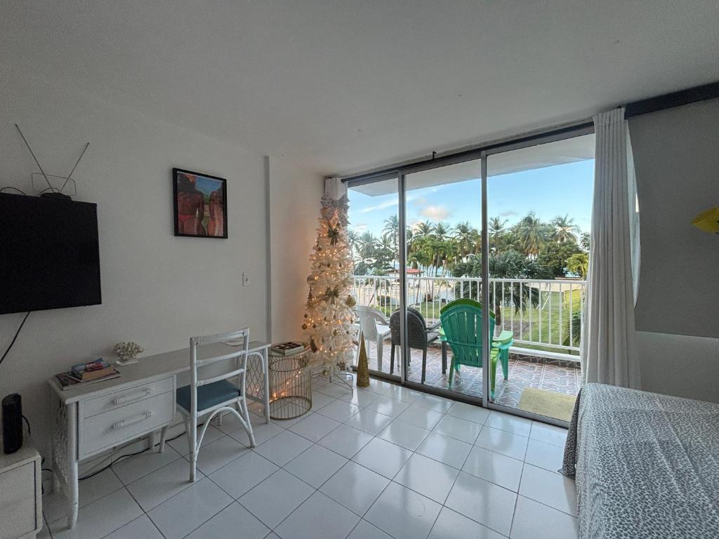 une chambre avec un bureau et une vue sur un patio dans l'établissement Hobie Beachfront Apartment Isla Verde, à San Juan