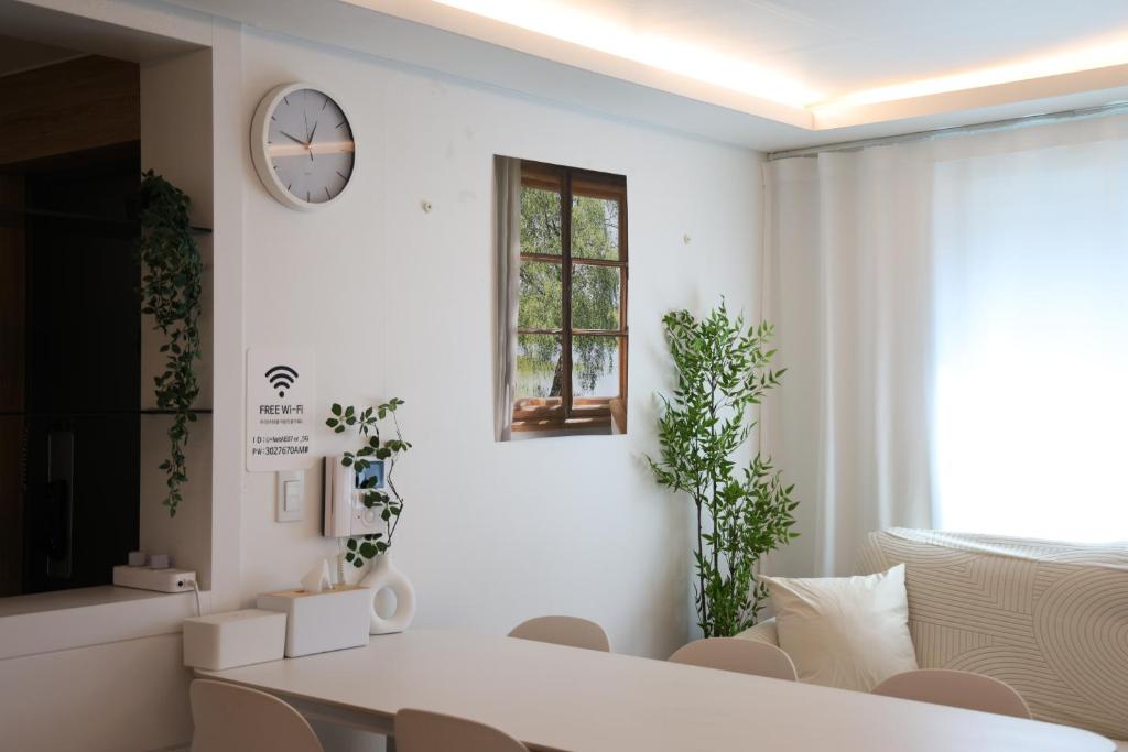 a white room with a table and a clock on the wall at HONGDAE t HOUSE in Seoul