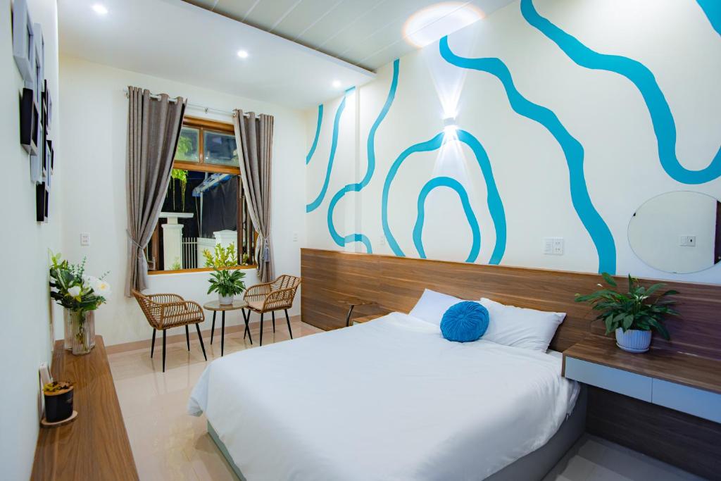a bedroom with a bed with a blue painting on the wall at Villa De Doc Let Homestay in Nha Trang