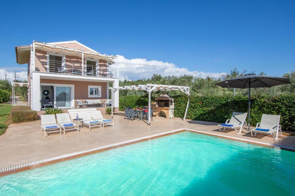 a house with a swimming pool with chairs and an umbrella at Villa Casa Di Billy in Halikounas