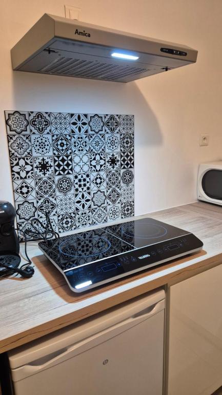 een keuken met een kookplaat met een tegelwand bij Studio La Pause d'un Soir in Roye