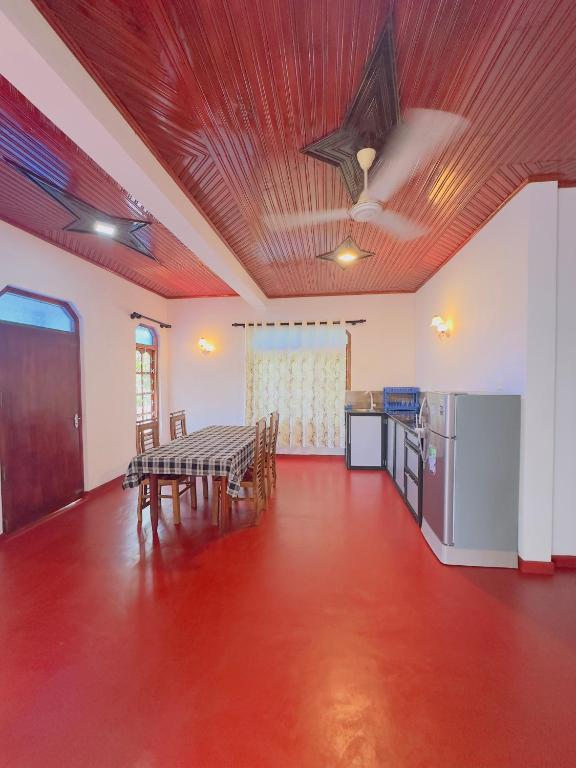a dining room with a table and a kitchen at Goyambokka Richard Home Stay in Tangalle