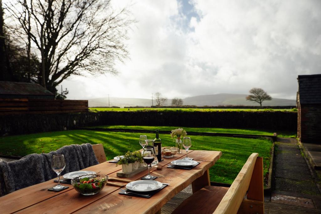 a wooden table with plates and wine glasses on it at Homely Cottage - Beaches, Costal walks, Castles in Newchapel